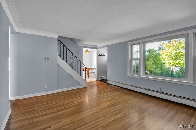 unfurnished living room with hardwood / wood-style flooring, crown molding, a baseboard radiator, and an inviting chandelier