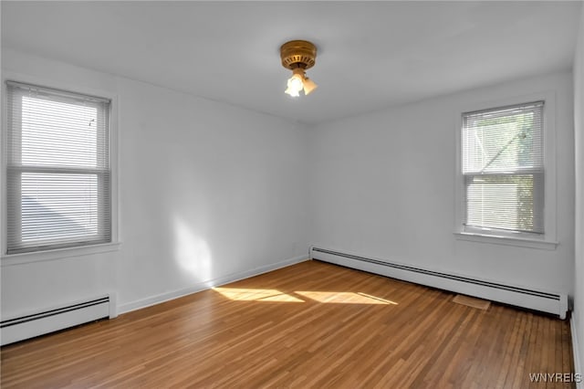 empty room with hardwood / wood-style floors and a baseboard heating unit