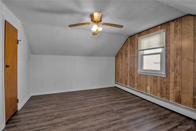 bonus room with lofted ceiling, wooden walls, a baseboard radiator, and dark hardwood / wood-style flooring