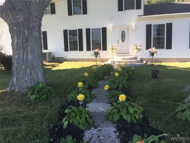 view of exterior entry with a yard and central AC unit