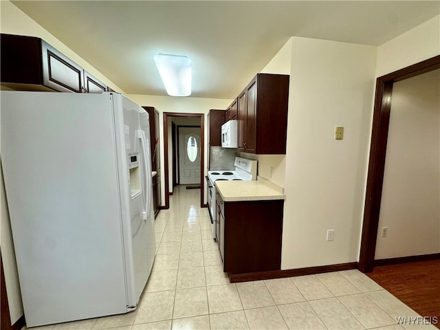 kitchen featuring dark brown cabinetry, white appliances, and light tile patterned floors