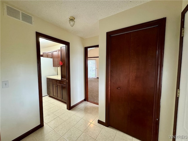 hall featuring a textured ceiling and light tile patterned flooring