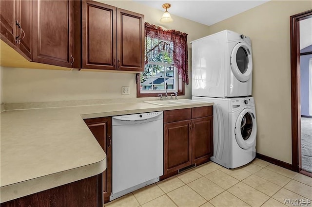 clothes washing area with sink, stacked washer / drying machine, and light tile patterned floors