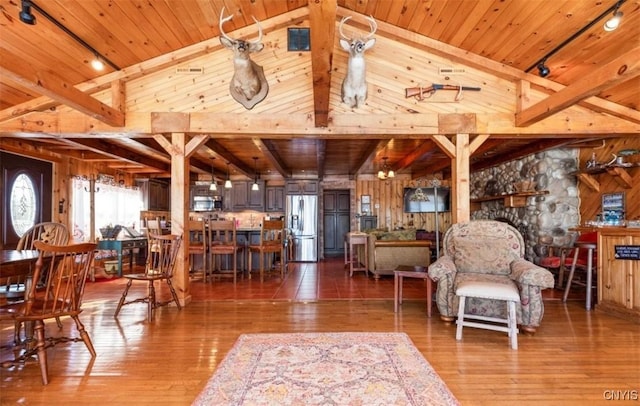 living area with wood walls, wood ceiling, lofted ceiling with beams, and hardwood / wood-style floors