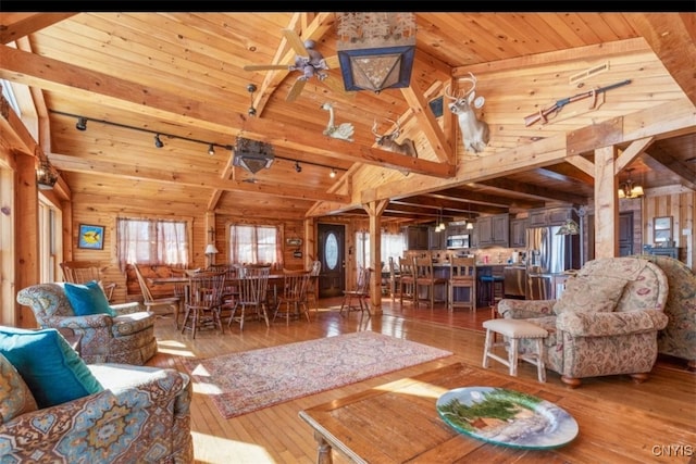 living room featuring wood walls, wood-type flooring, wooden ceiling, and lofted ceiling with beams