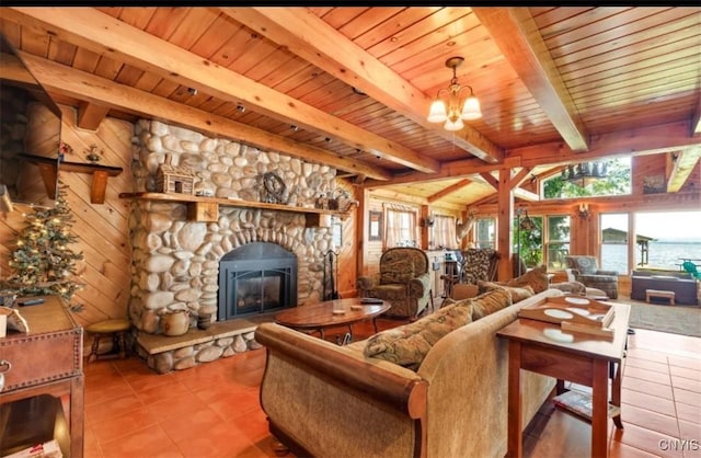 living room featuring tile patterned floors, beamed ceiling, wood ceiling, a notable chandelier, and a stone fireplace