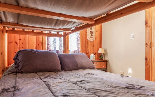 bedroom with wooden walls and beam ceiling