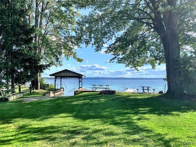 view of dock with a water view, a gazebo, and a lawn