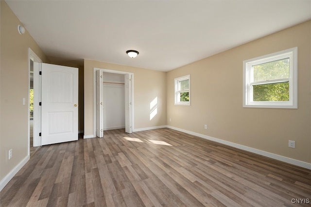 unfurnished bedroom with multiple windows and dark hardwood / wood-style flooring