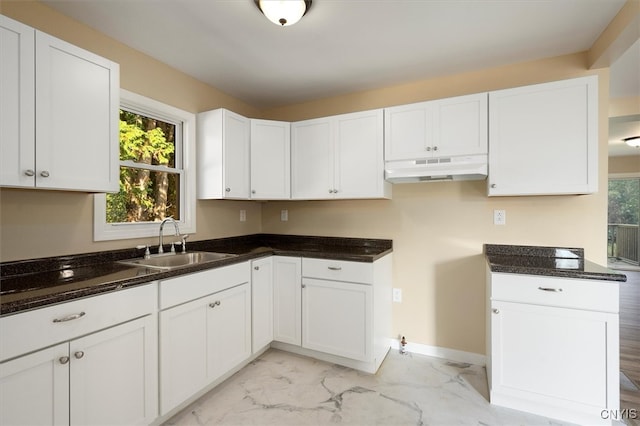 kitchen with dark stone countertops, sink, and white cabinets