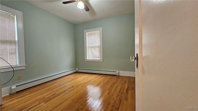 empty room featuring light wood-type flooring, ceiling fan, and a baseboard heating unit