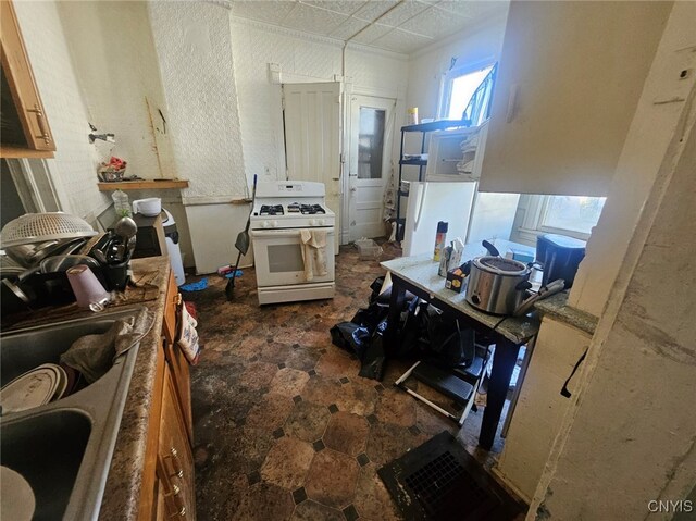 kitchen with white range with gas cooktop and light brown cabinetry