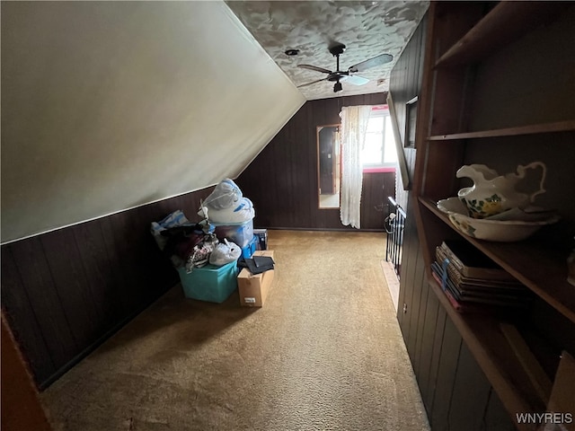 bonus room with wood walls, light carpet, lofted ceiling, and ceiling fan