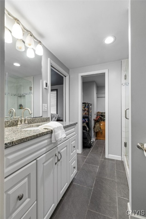 bathroom with tile patterned flooring, walk in shower, and vanity