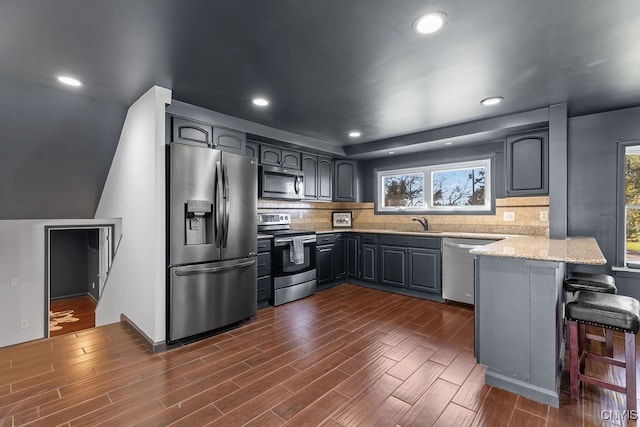 kitchen featuring kitchen peninsula, a healthy amount of sunlight, stainless steel appliances, and a breakfast bar