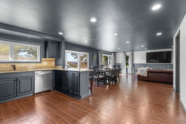 kitchen featuring dark hardwood / wood-style floors, sink, kitchen peninsula, gray cabinets, and dishwasher