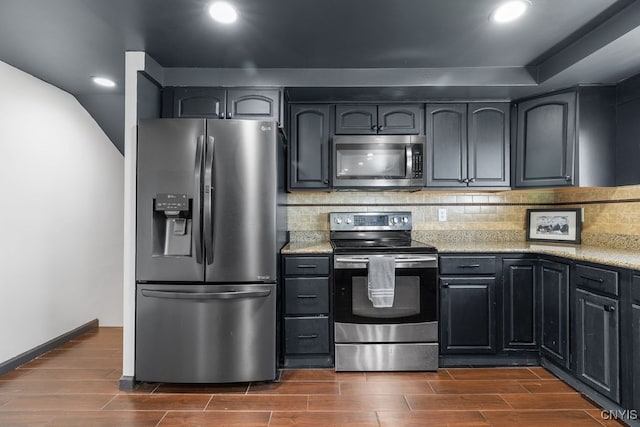 kitchen with light stone countertops, appliances with stainless steel finishes, backsplash, and dark hardwood / wood-style flooring