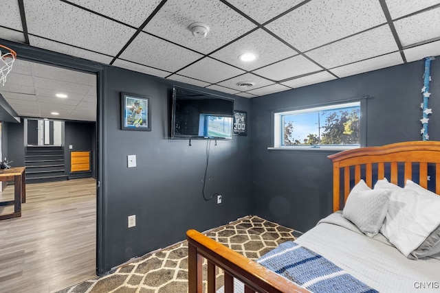 bedroom with wood-type flooring and a drop ceiling