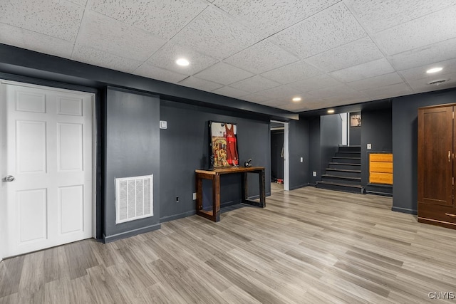 interior space featuring a paneled ceiling and light hardwood / wood-style flooring