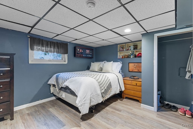 bedroom with a drop ceiling and light hardwood / wood-style flooring