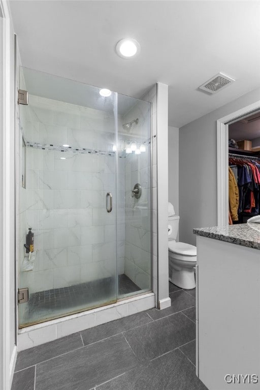 bathroom featuring tile patterned floors, a shower with shower door, vanity, and toilet