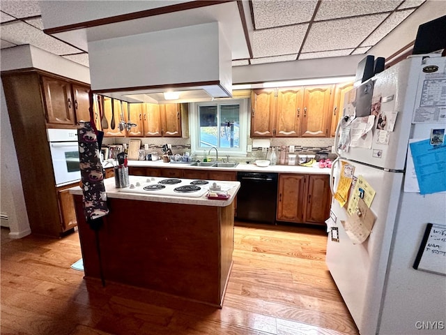 kitchen with sink, white appliances, exhaust hood, a drop ceiling, and light hardwood / wood-style floors