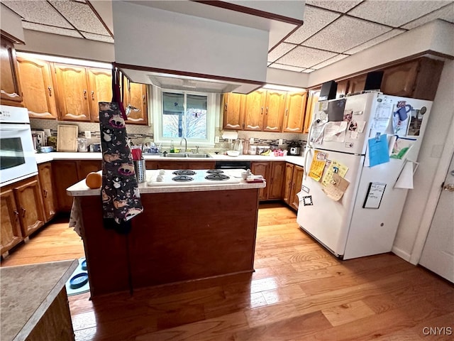 kitchen featuring light hardwood / wood-style floors, white appliances, a paneled ceiling, sink, and decorative backsplash