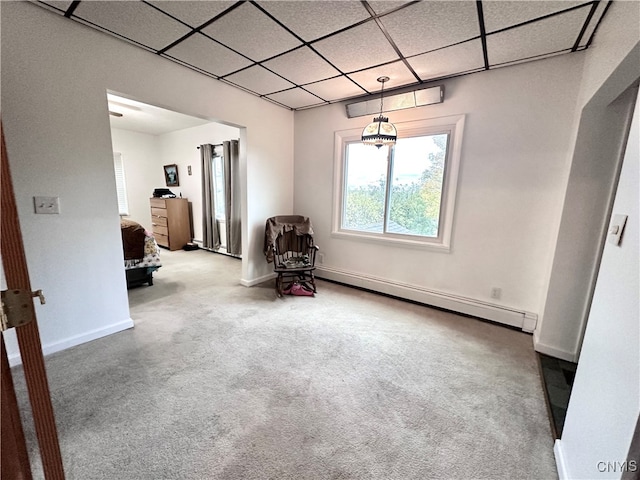 unfurnished room featuring carpet, a drop ceiling, and a baseboard heating unit