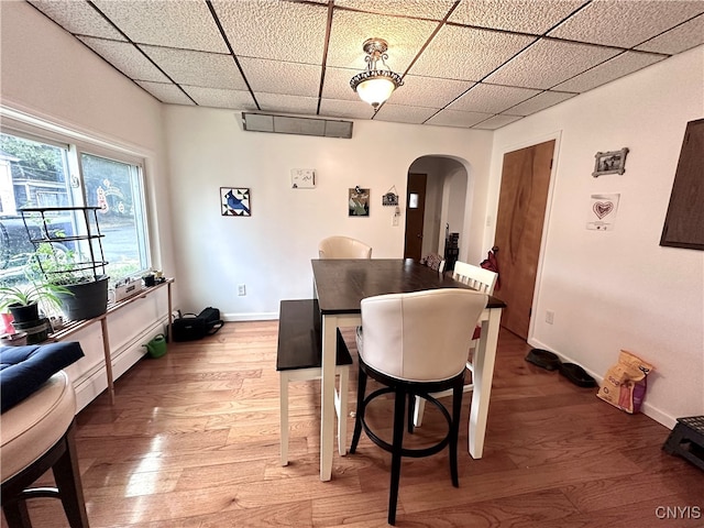 dining area featuring wood-type flooring and a drop ceiling