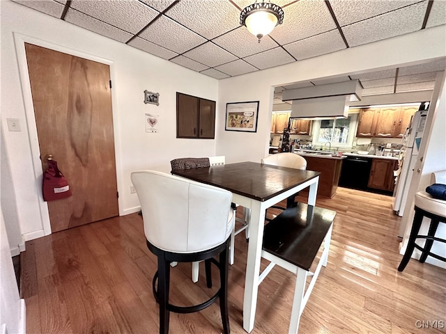 dining space featuring a drop ceiling and light hardwood / wood-style flooring