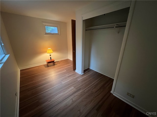 unfurnished bedroom featuring a closet and dark wood-type flooring