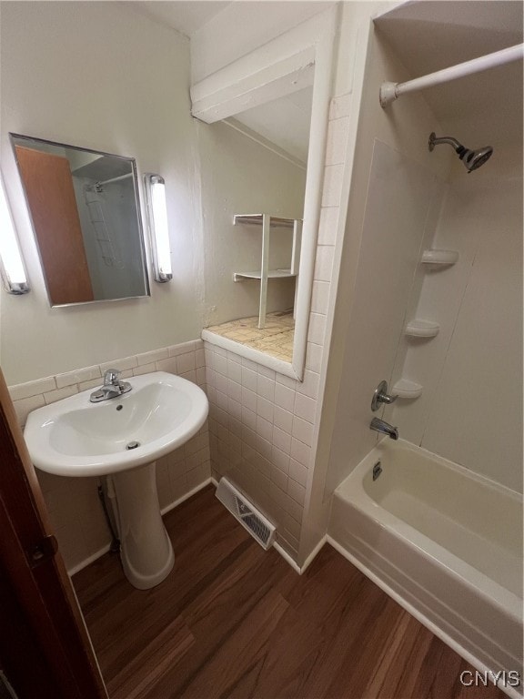 bathroom featuring hardwood / wood-style floors, shower / tub combination, and tile walls