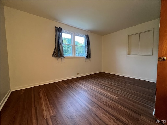 unfurnished room with dark wood-type flooring