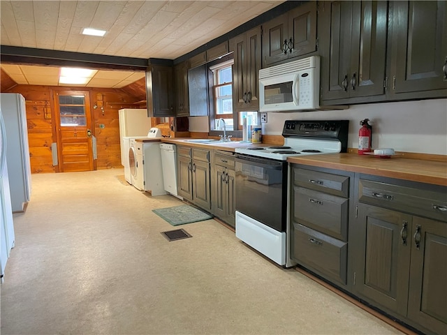 kitchen featuring wooden counters, white appliances, light colored carpet, sink, and wood walls