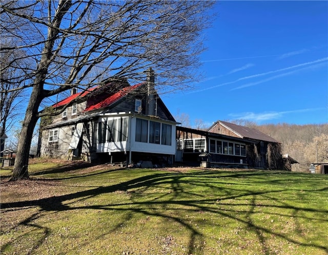 rear view of property featuring a sunroom and a yard