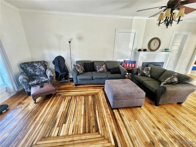 living room with ceiling fan, hardwood / wood-style flooring, a tiled fireplace, and ornamental molding