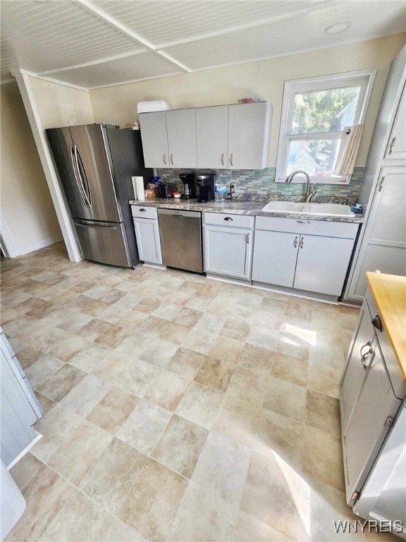 kitchen featuring stainless steel appliances, sink, white cabinetry, and decorative backsplash