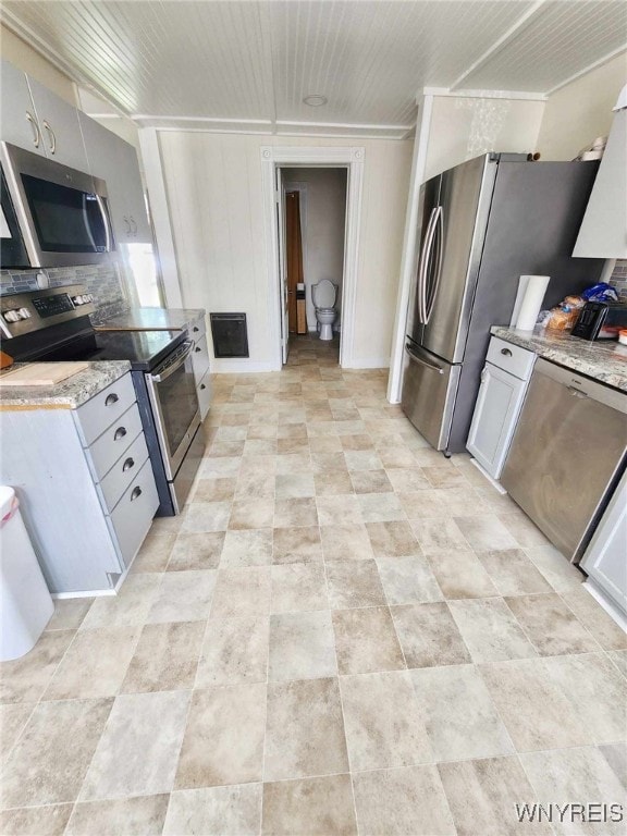 kitchen with stainless steel appliances, ornamental molding, tasteful backsplash, and white cabinetry