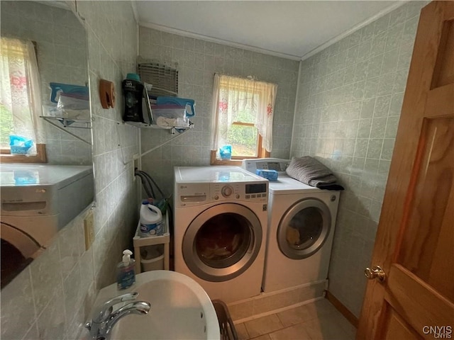 clothes washing area with tile patterned floors, washer and dryer, and tile walls