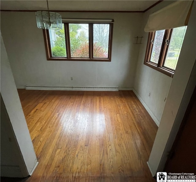 unfurnished room featuring a baseboard heating unit, a chandelier, and light hardwood / wood-style floors