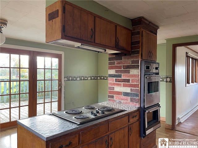 kitchen with stovetop, double oven, and light wood-type flooring