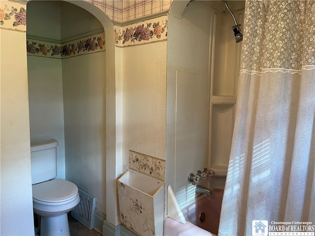 bathroom featuring toilet and shower / bathtub combination with curtain