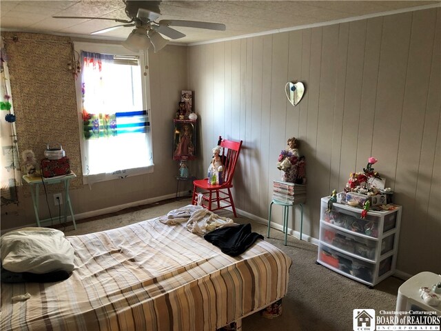 carpeted bedroom with crown molding, wooden walls, and ceiling fan