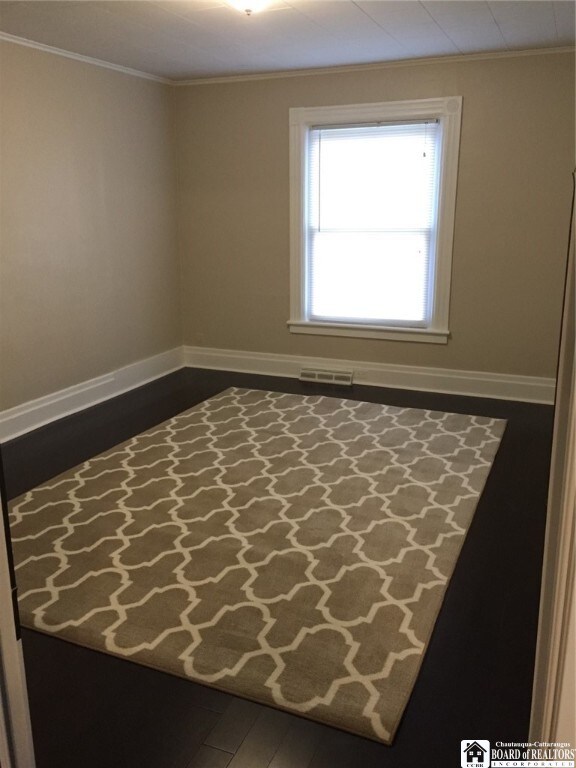 unfurnished room with hardwood / wood-style floors and crown molding