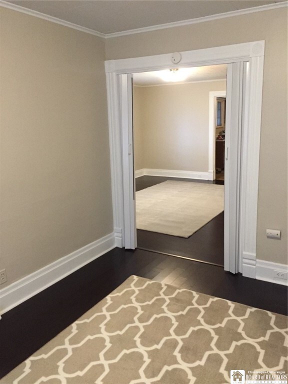 spare room featuring ornamental molding and dark wood-type flooring