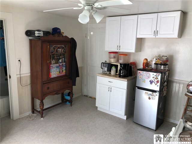 kitchen with stainless steel fridge, white cabinets, and ceiling fan