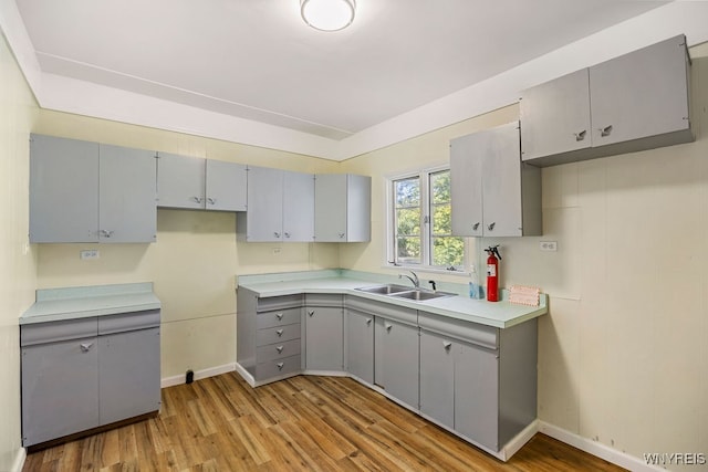 kitchen featuring gray cabinets, sink, and light wood-type flooring