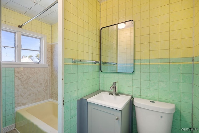 full bathroom featuring vanity, tile walls, toilet, and washtub / shower combination