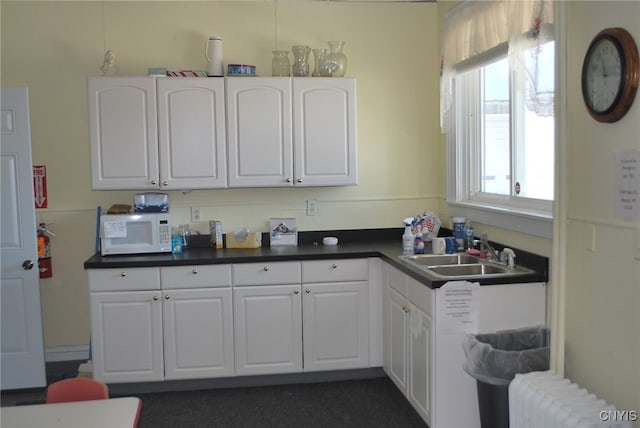 kitchen with white cabinets, radiator, and sink