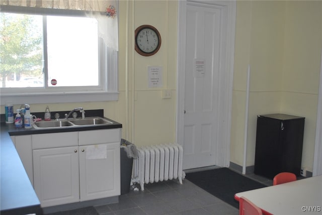 kitchen with sink, radiator heating unit, and white cabinetry